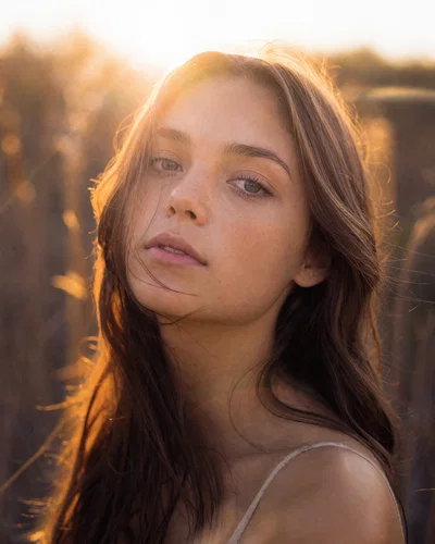 Backlit golden-hour close-up with rim light, reflector fill, and soft film-like flare.