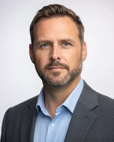 Bearded man in gray blazer on cool-white seamless with crisp rim along jawline.