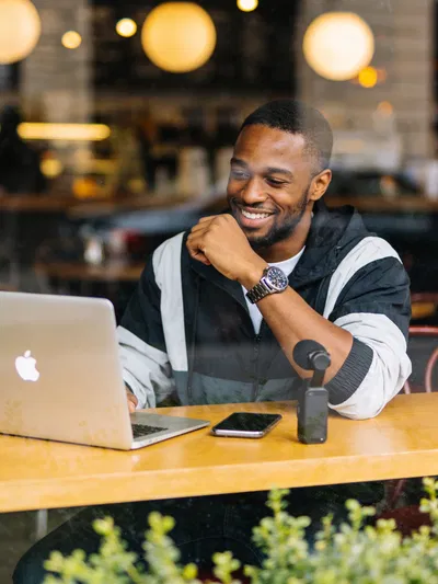 Black man editing Instagram photos at a café with creator gear