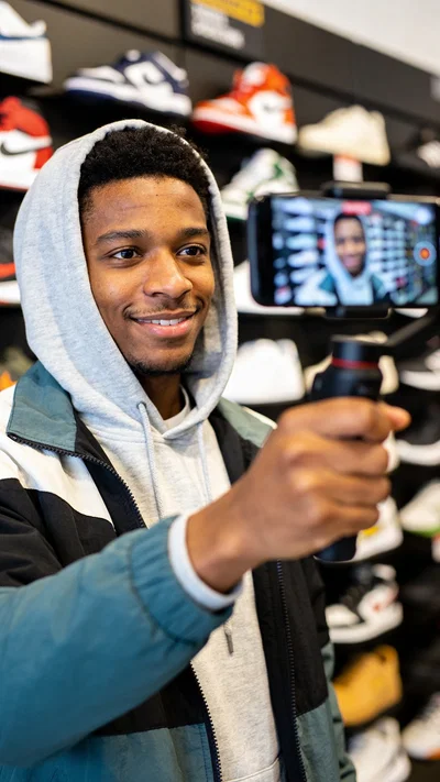 Black man filming product B-roll in a store with a phone gimbal