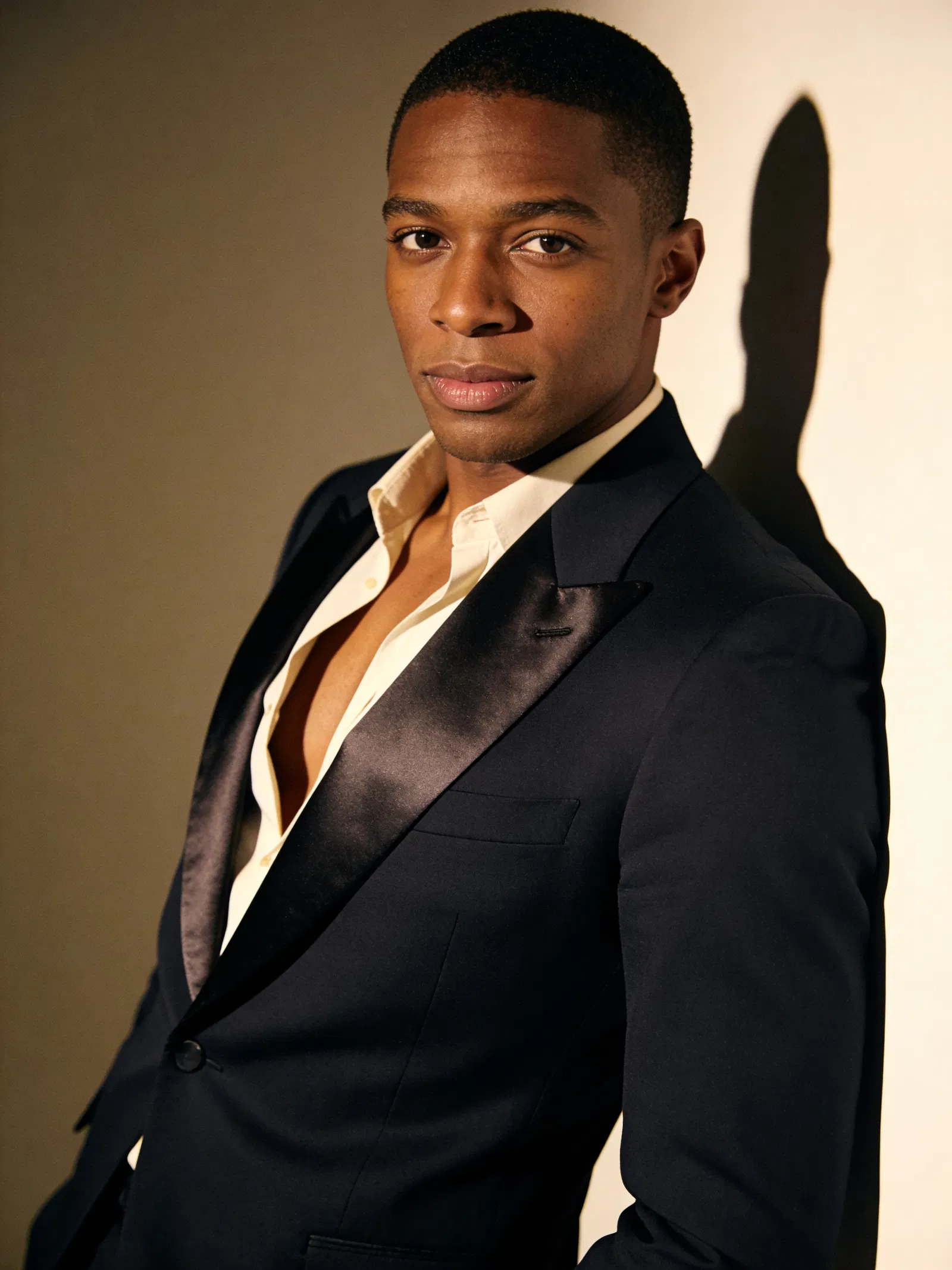 Black man in half-body tuxedo portrait with dramatic editorial studio lighting