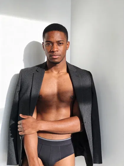 Black man in modern studio dudeoir portrait with blazer draped, high-key light
