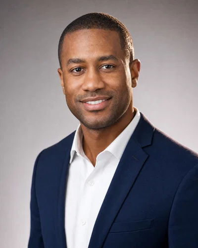 Black man in navy blazer on neutral gray seamless, soft key and rim light.
