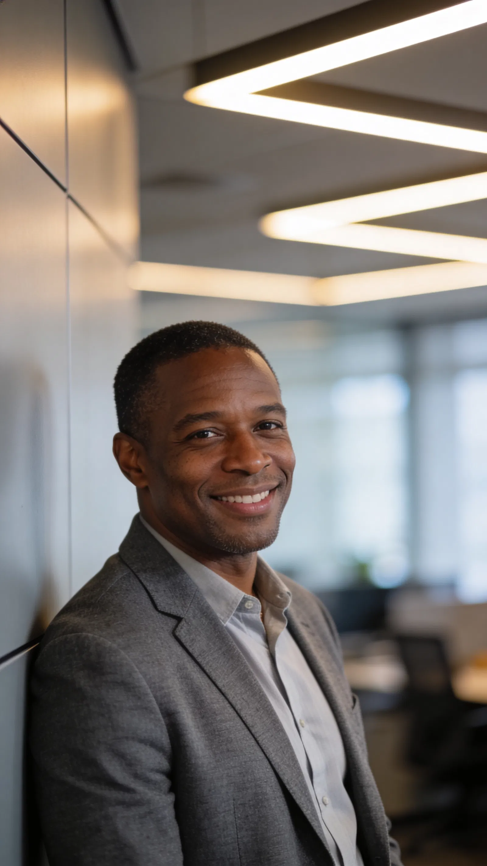 Black man leaning against office wall for confident, modern LinkedIn headshot