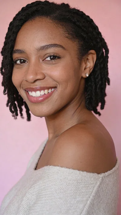 Black woman studio headshot on blush background with radiant smile