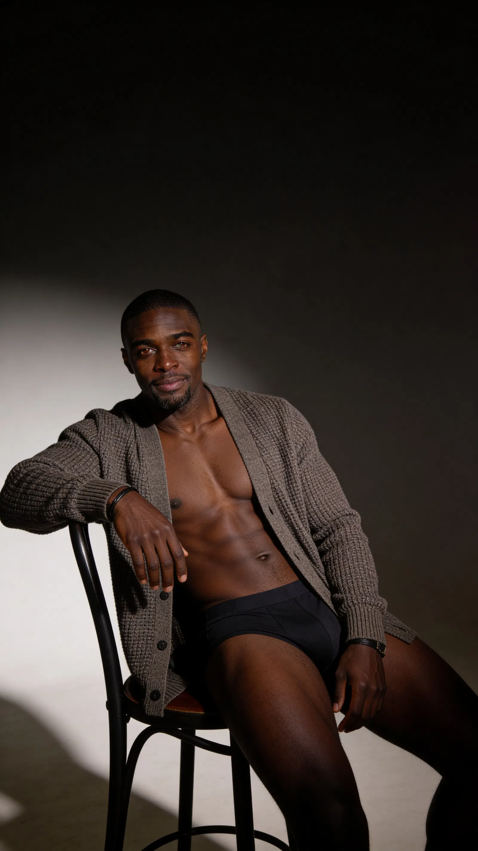 Consistent character in moody studio male boudoir scene with rim lighting and cardigan
