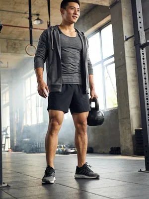 East Asian man with kettlebell in industrial gym portrait
