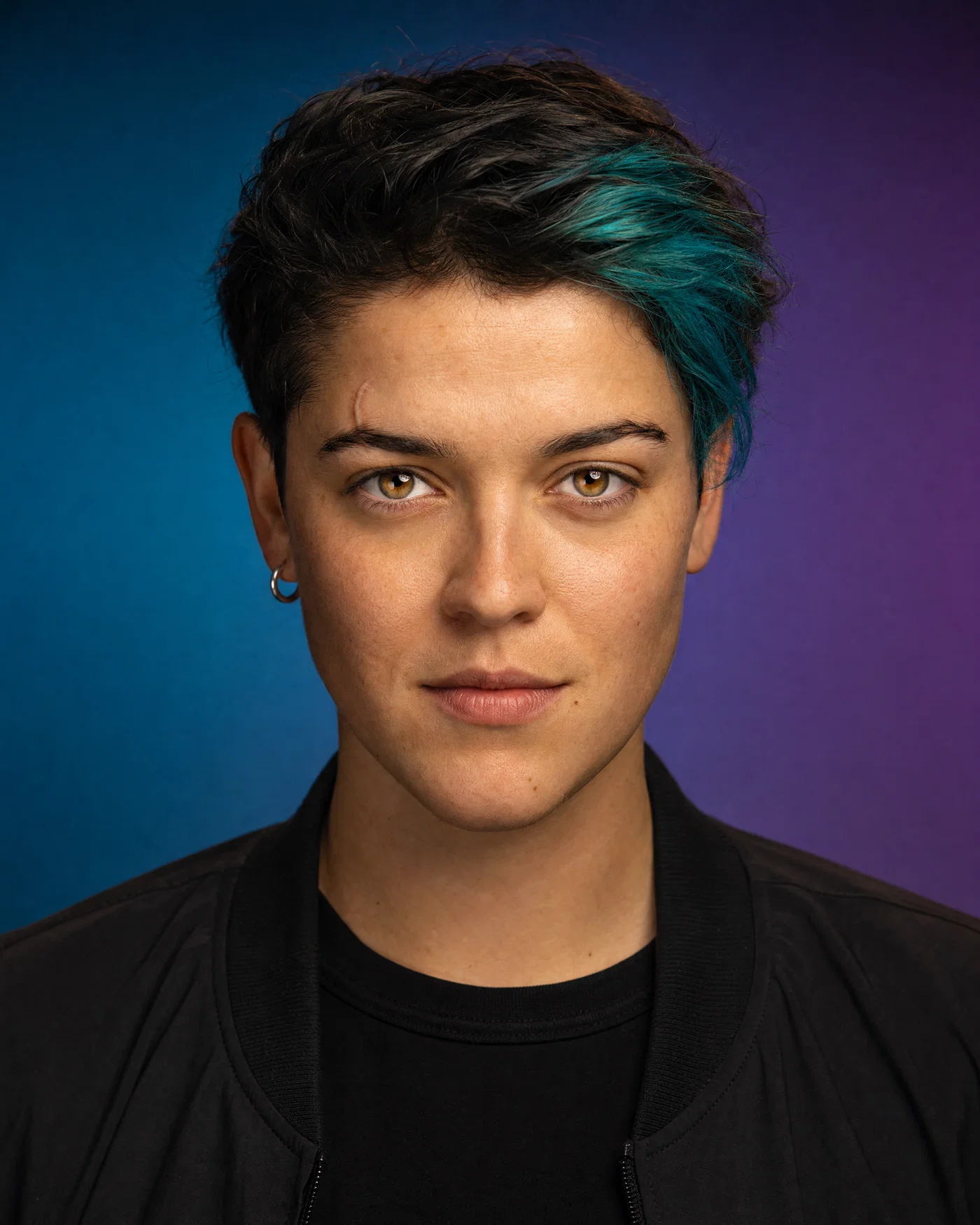 Editorial studio avatar with gel-lit teal-to-purple gradient background and crisp catchlights.