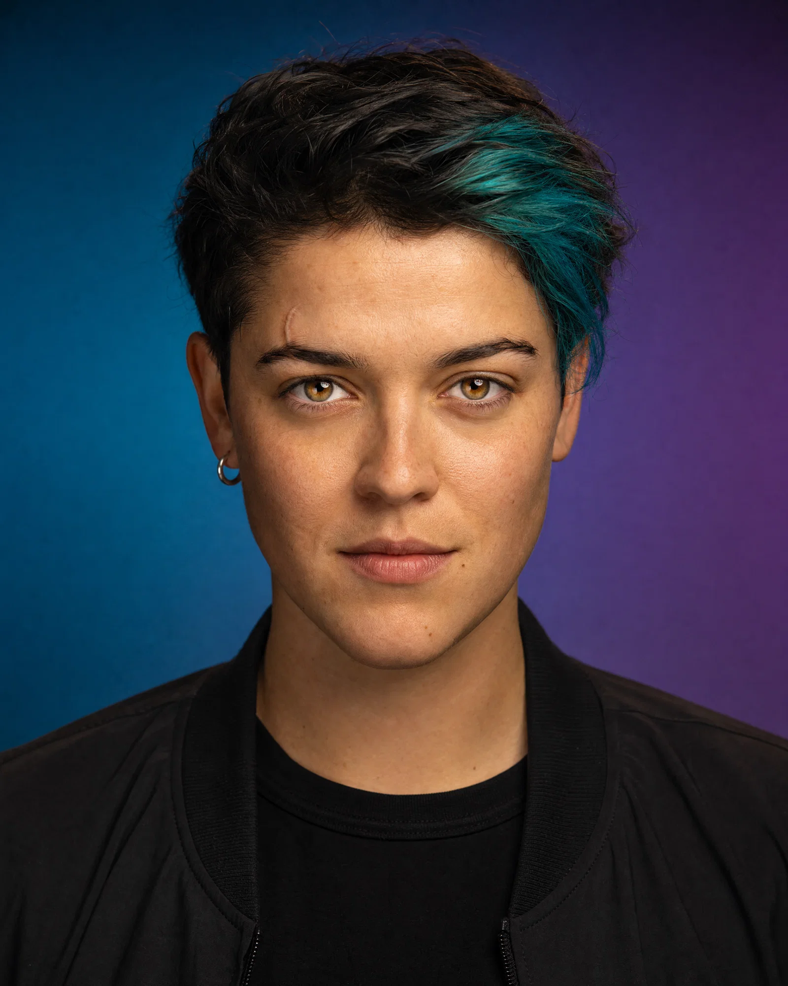 Editorial studio avatar with gel-lit teal-to-purple gradient background and crisp catchlights.