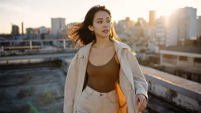 Golden-hour rooftop editorial portrait with backlit rim light and subtle flare.