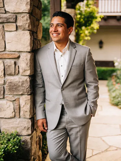 Hispanic groom in light gray suit garden courtyard portrait