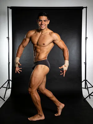 Hispanic male bodybuilder full-body studio portrait with rim lighting and physique emphasis