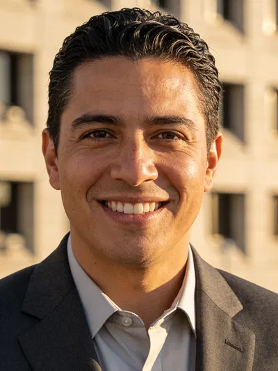Hispanic man in suit outdoors with soft golden-hour resume photo