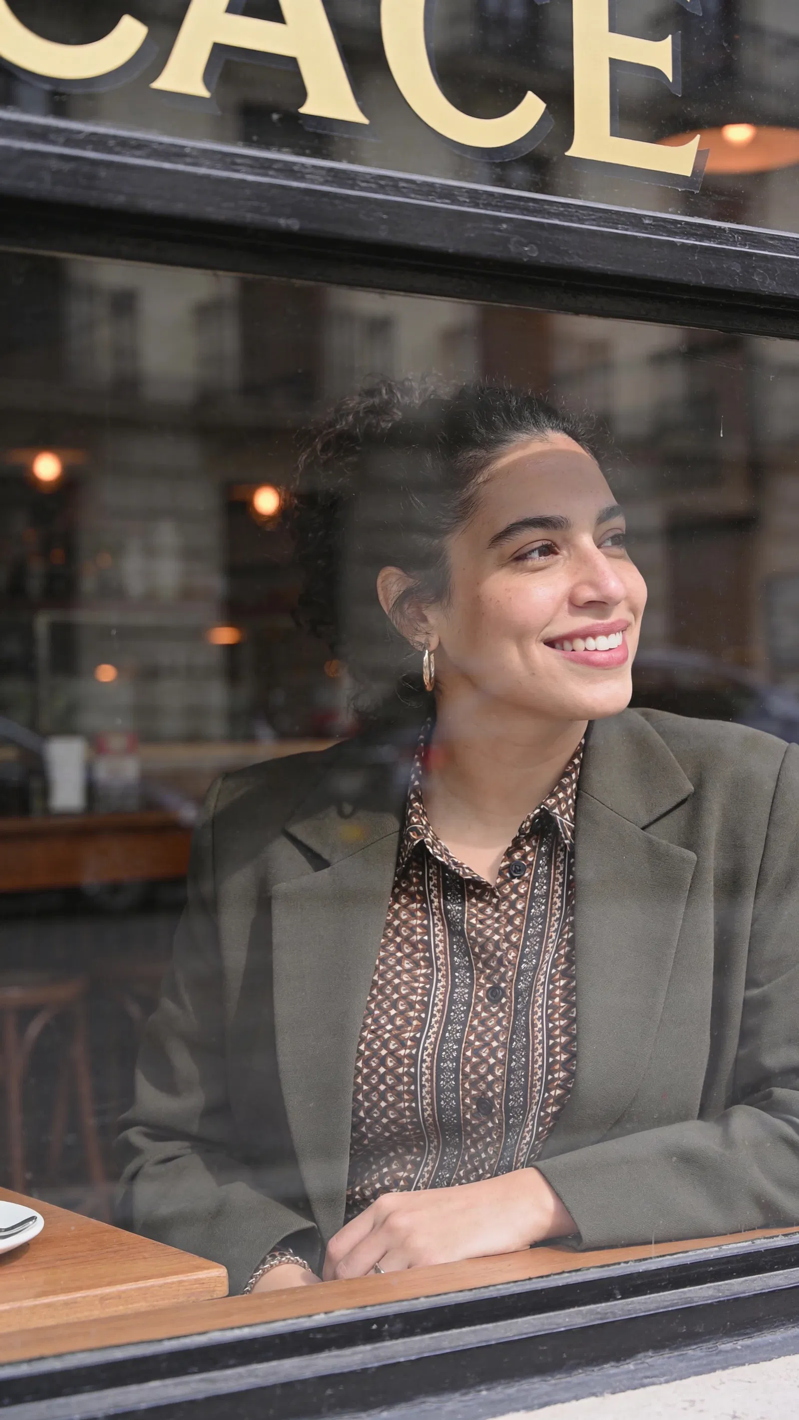 Hispanic woman by café window half-body editorial fashion portrait