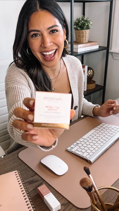 Latina woman filming an unboxing-style Instagram Reel in a home office