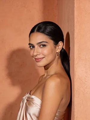 Latina woman head-and-shoulders boudoir portrait against warm textured wall