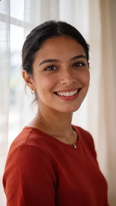 Latina woman in window light, natural head-and-shoulders dating profile photo.