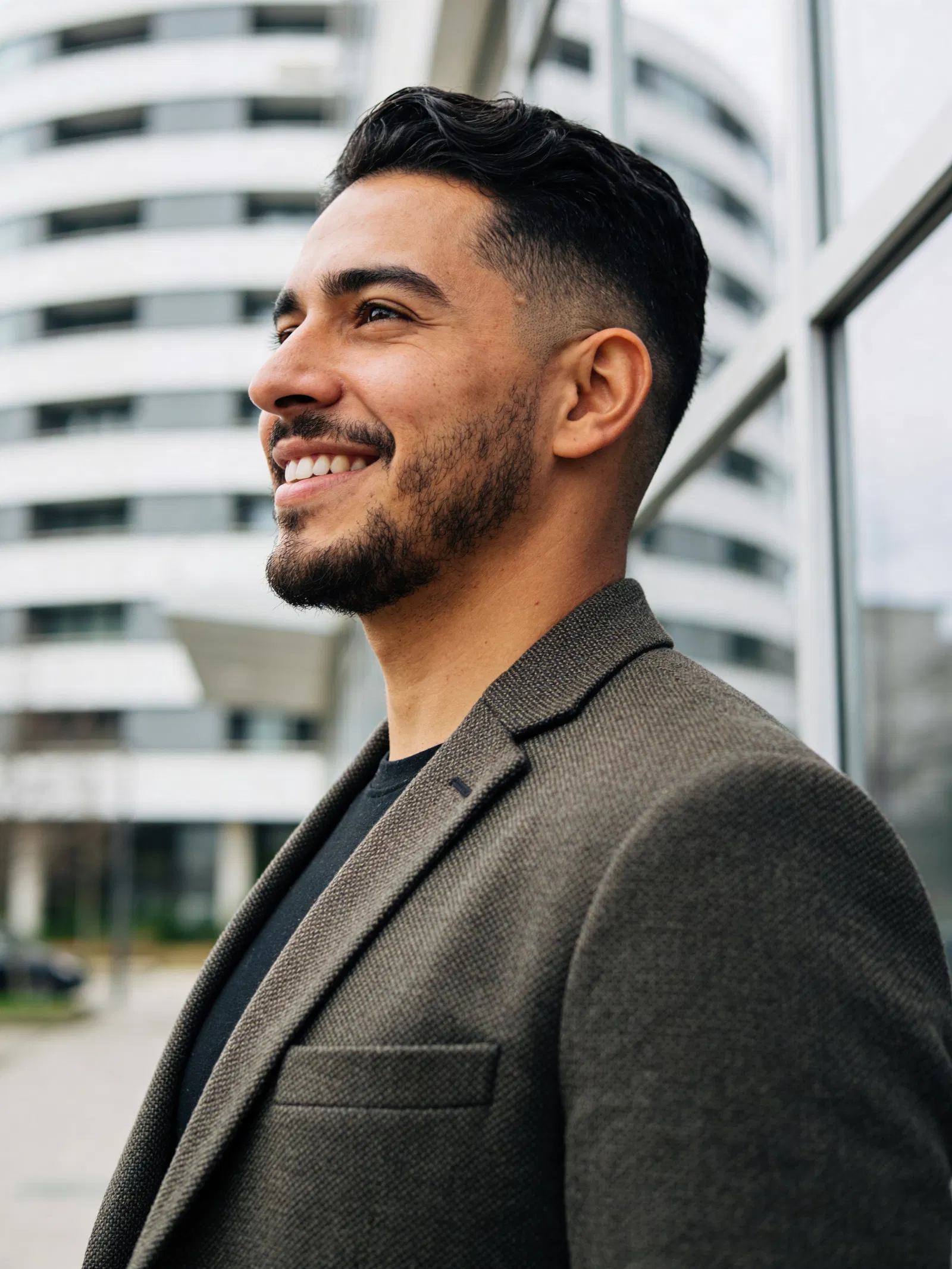 Latino man outdoors near modern building for profile photo
