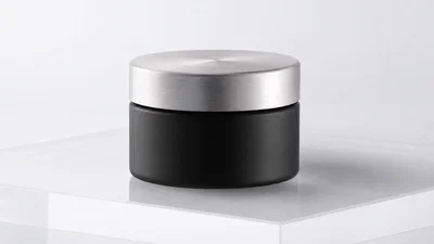 Matte black skincare jar on white seamless, softbox lighting and subtle reflection.