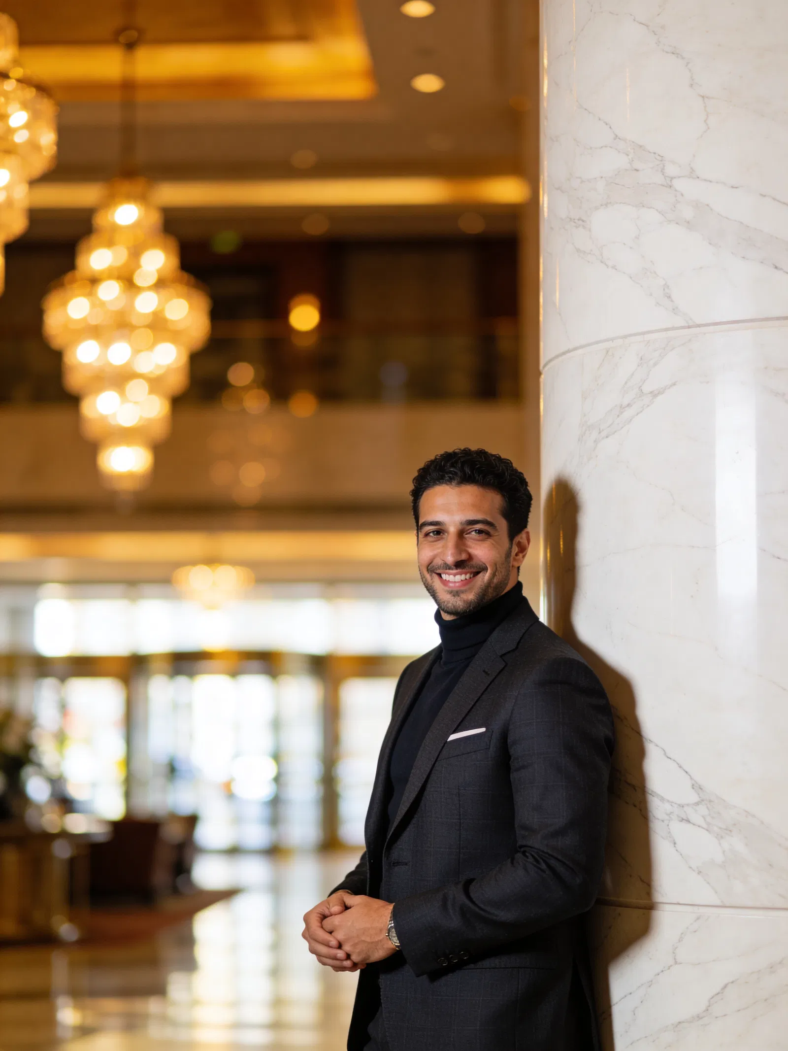 Middle Eastern man in hotel lobby portrait with warm bokeh and tailored blazer