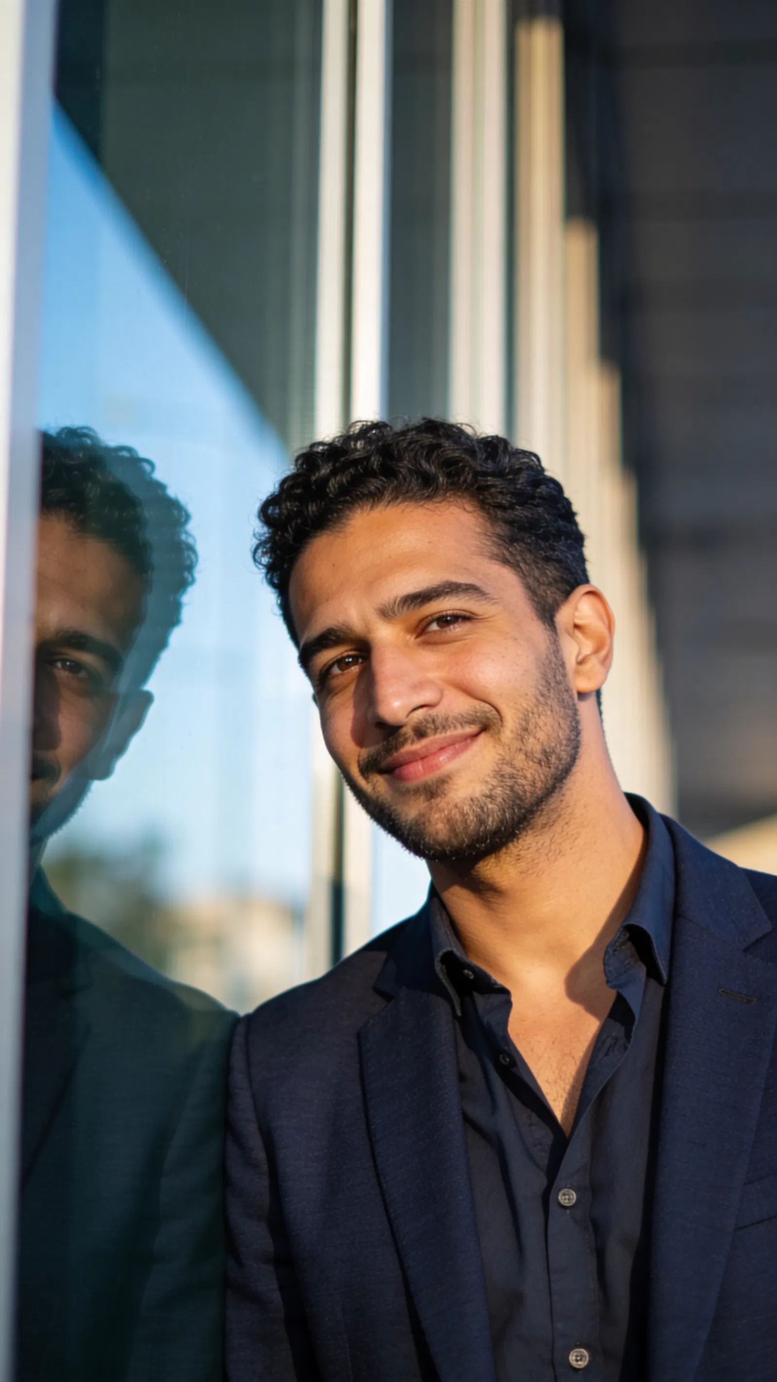 Middle Eastern man near glass wall, modern half-body professional headshot