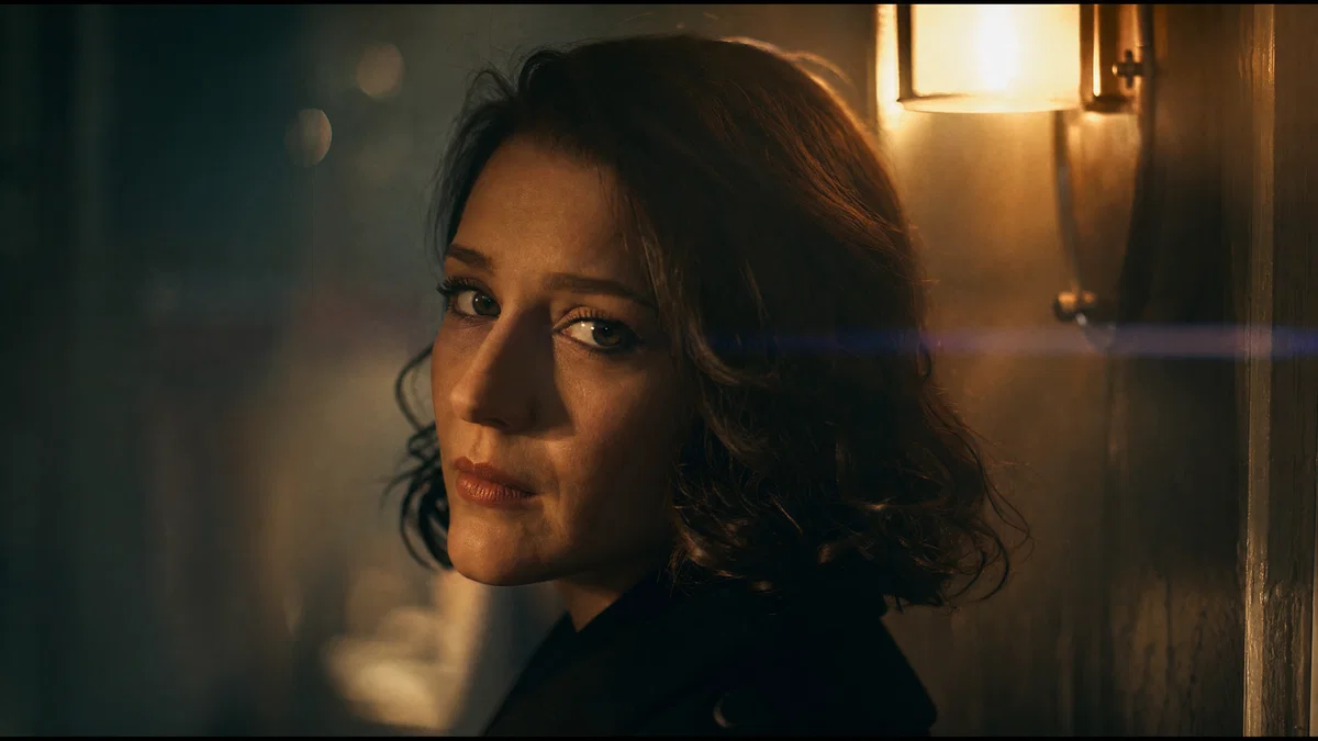 Moody close-up portrait with practical tungsten light and subtle anamorphic flare.