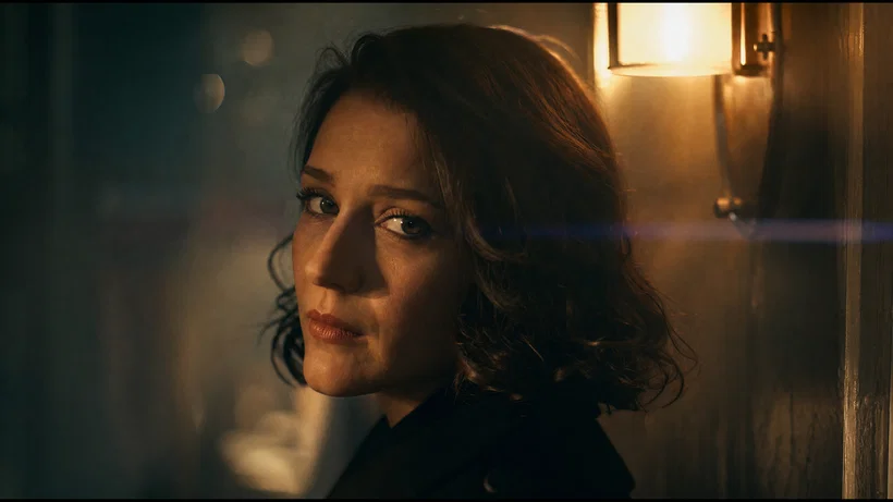 Moody close-up portrait with practical tungsten light and subtle anamorphic flare.
