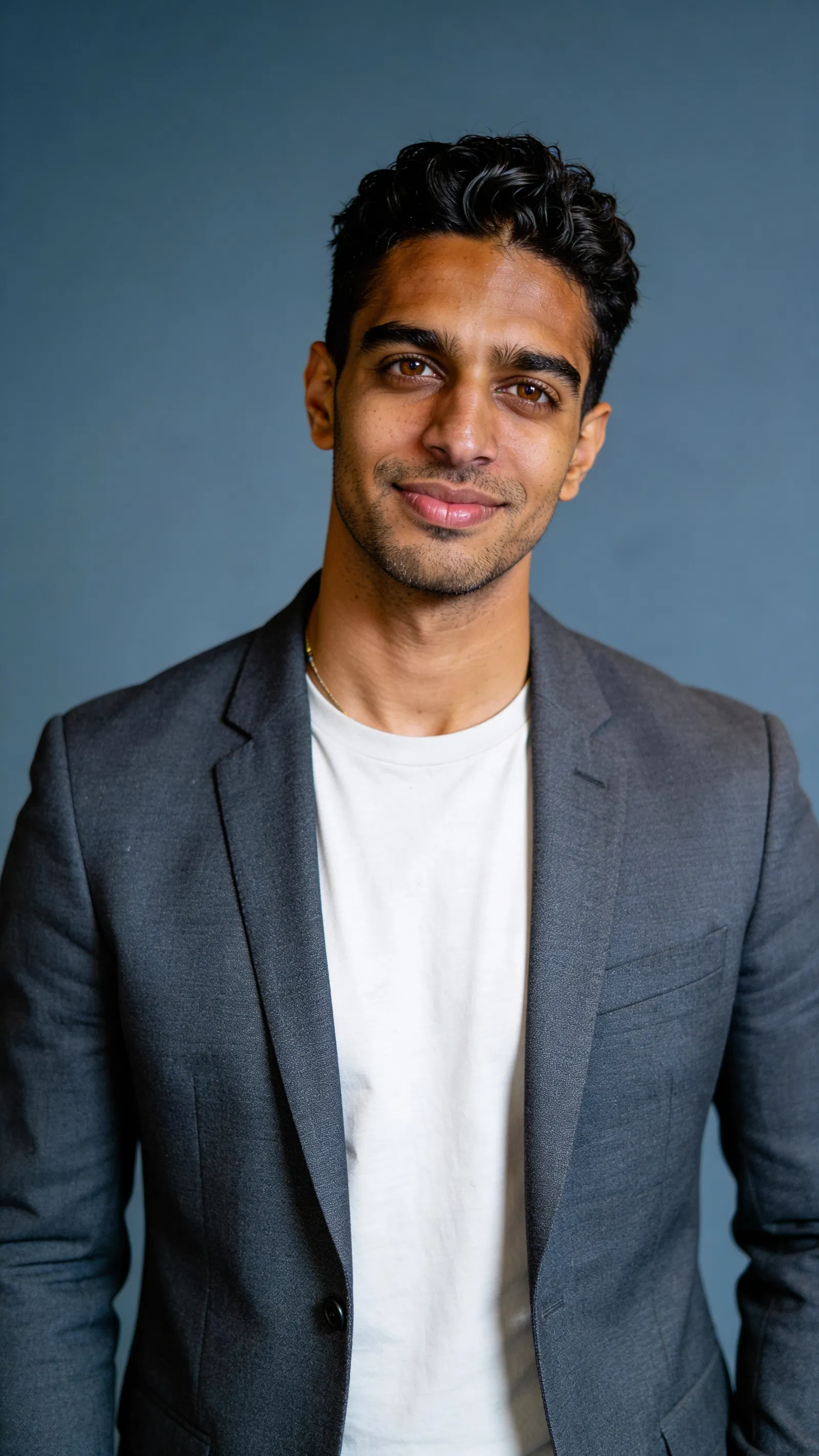 Same character on blue-gray backdrop with directional studio lighting and gray blazer