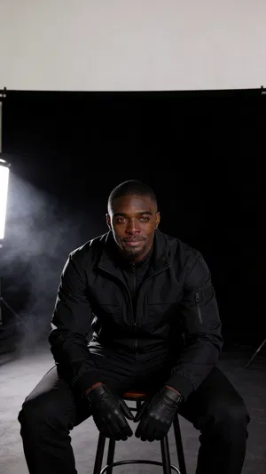 Same character stealth cosplay seated in dramatic low-key studio