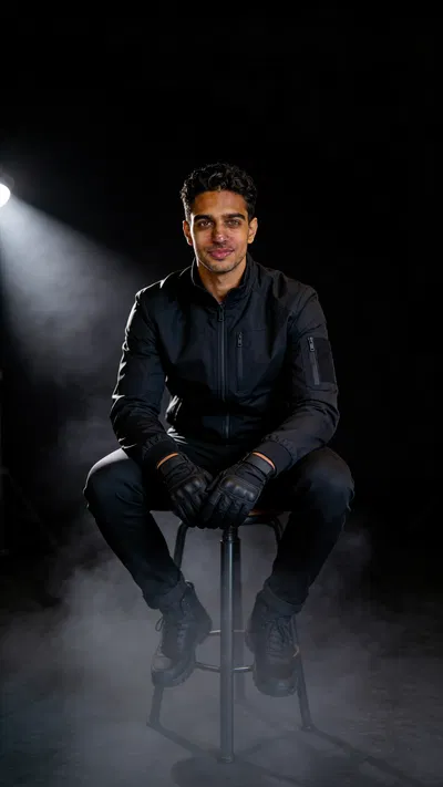 Same character stealth cosplay seated in dramatic low-key studio