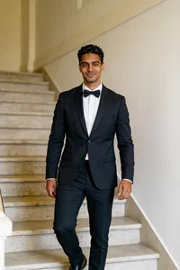 Same groom character walking on venue staircase in tux 2:3