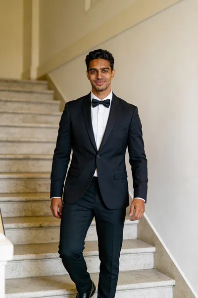 Same groom character walking on venue staircase in tux 2:3