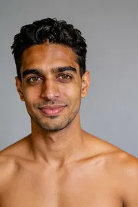 Same man studio headshot, subtle smile, authentic dating app photo