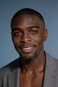 Same person on blue-gray backdrop with clean CV headshot crop