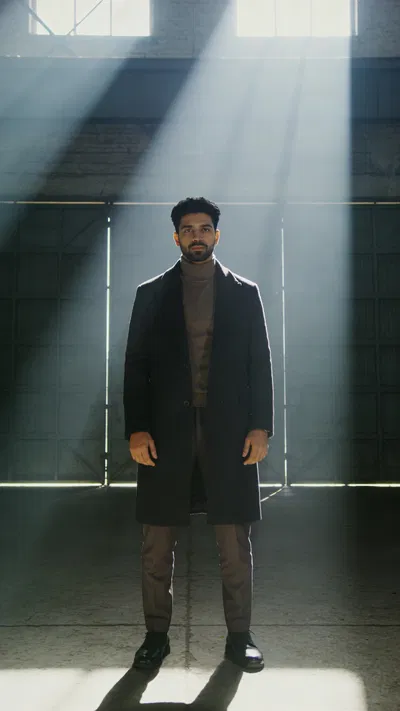 South Asian man full-body warehouse editorial portrait with dramatic light beams