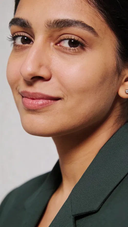 South Asian woman in studio headshot with clean gray background