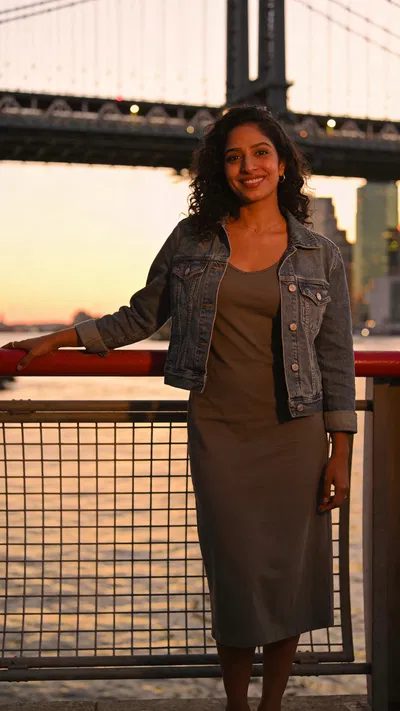 South Asian woman on bridge at sunset, confident full-body dating app photo.