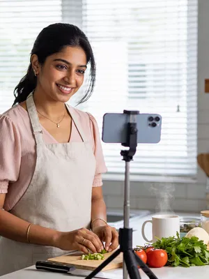South Asian woman recording an Instagram recipe Reel in a bright kitchen