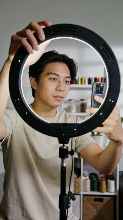 Southeast Asian man adjusting a ring light before filming Instagram content