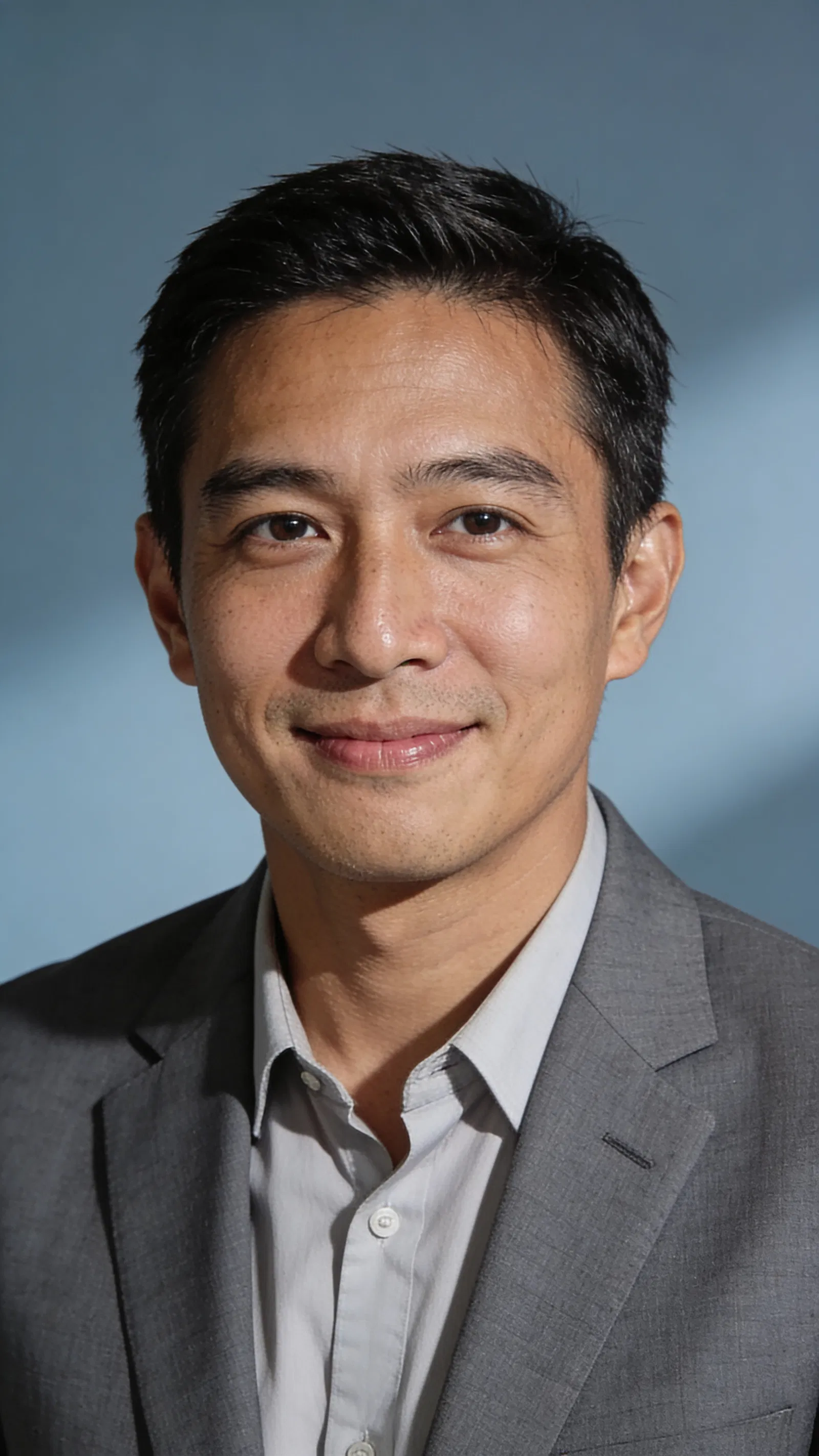 Southeast Asian man in gray suit with clean studio resume headshot