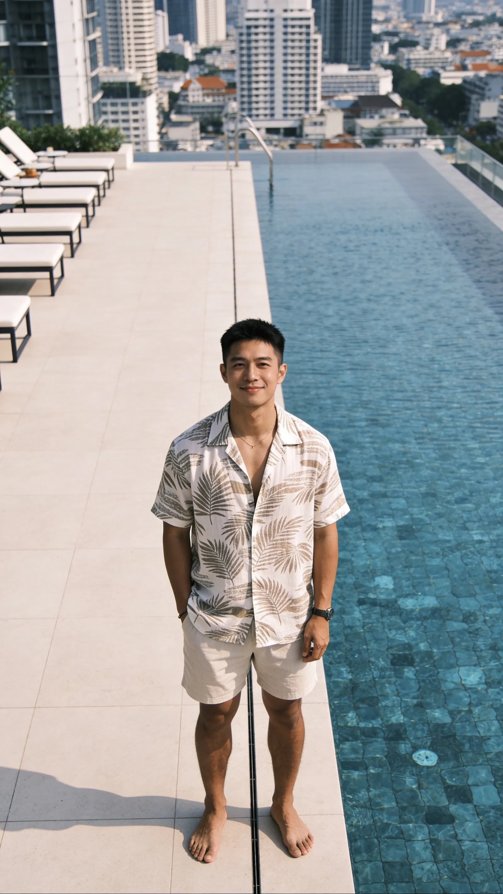 Southeast Asian man on rooftop pool deck, clean travel lifestyle full-body portrait.