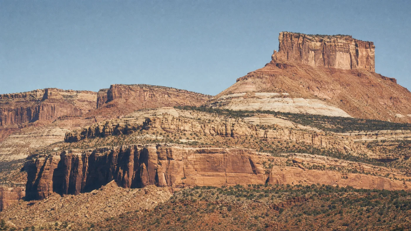 Telephoto canyon mesas with compressed layers, harsh midday shadows, and warm Kodak Gold tone.