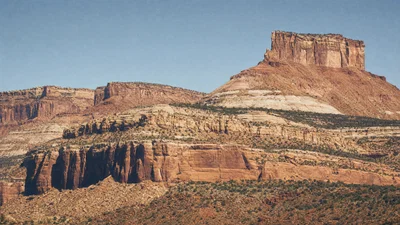 Telephoto canyon mesas with compressed layers, harsh midday shadows, and warm Kodak Gold tone.