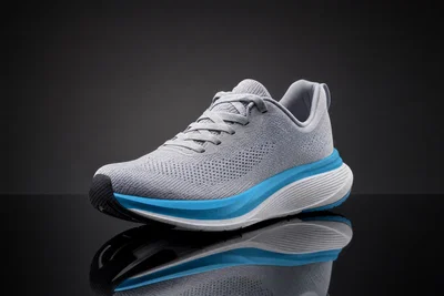 Three-quarter sneaker hero shot on glossy black acrylic with strip softbox texture and clean reflection.