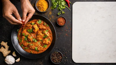 Top-down cooking scene with spices falling and a clean cutting-board area for headline text