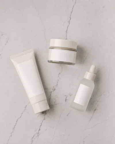 Top-down flat lay of skincare products on light gray marble with even overhead softbox lighting.