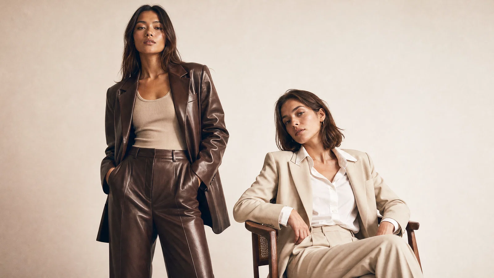 Two-model studio lookbook photo on warm white seamless with soft key and shoulder separation.