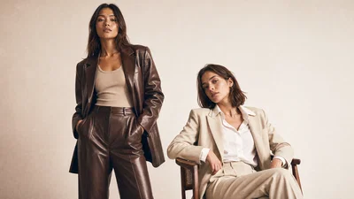 Two-model studio lookbook photo on warm white seamless with soft key and shoulder separation.