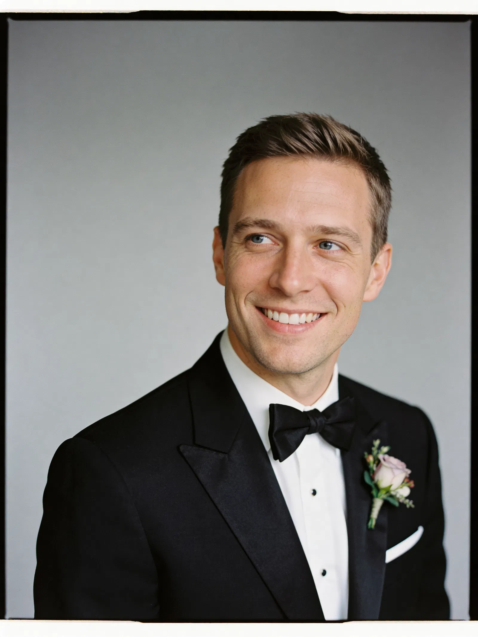 White groom in tuxedo studio headshot with confident smile