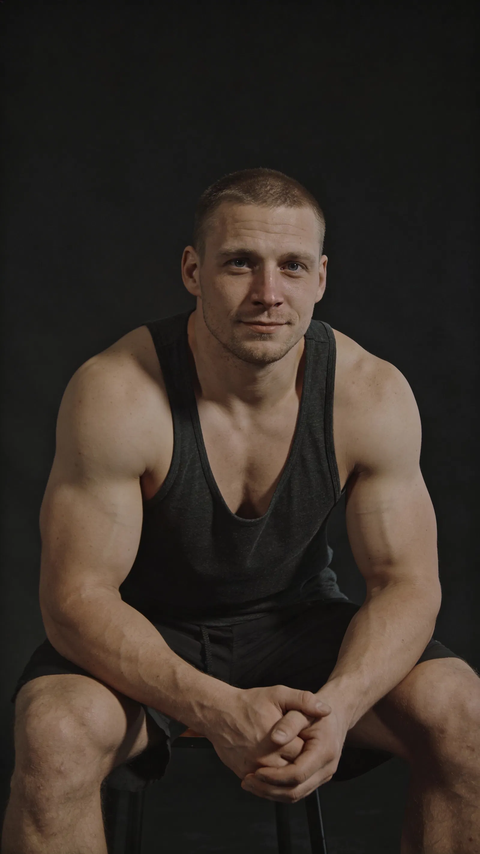 White male bodybuilder seated half-body studio portrait with cinematic lighting